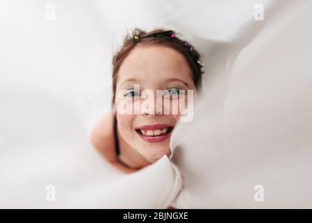 Portrait d'une jeune fille portant un maquillage enveloppé dans un rideau Banque D'Images