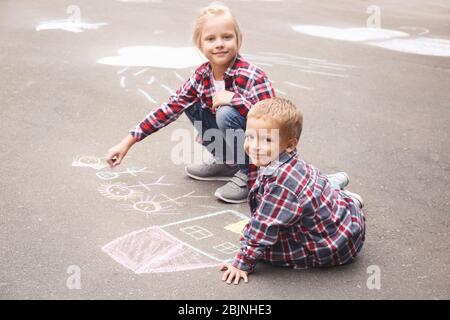 Les petits enfants qui dessinent la maison et la famille avec de la craie sur l'asphalte Banque D'Images