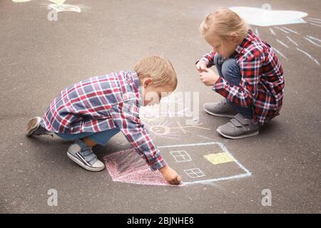 Les petits enfants qui dessinent la maison et la famille avec de la craie sur l'asphalte Banque D'Images