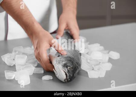 Chef mettant du saumon frais sur table dans la cuisine Banque D'Images