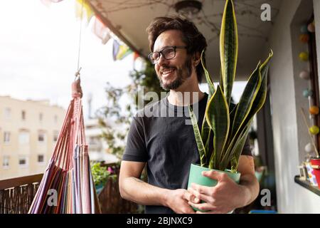 Jeune homme prenant soin de ses plantes sur un balcon Banque D'Images