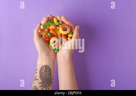 Femme tenant des bonbons colorés sur fond violet Banque D'Images