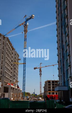 Grues sur le chantier de bâtiments de hauteur multi-unités. Construction d'une maison en béton moulé. Nouveaux bâtiments avec un grand nombre d'appartements Banque D'Images