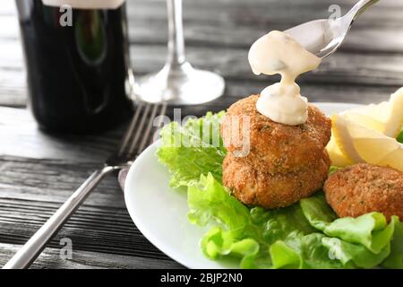 Verser la sauce sur les galettes de saumon dans la plaque Banque D'Images