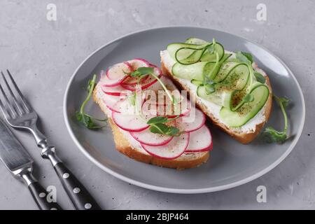 Deux sandwichs avec concombres, radis et pois microverts sur fond gris, gros plan Banque D'Images