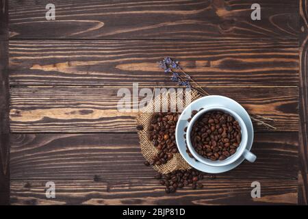 Tasse à café avec grains de café et branches de lavande sur un plan d'examen en bois. Vue de dessus Banque D'Images