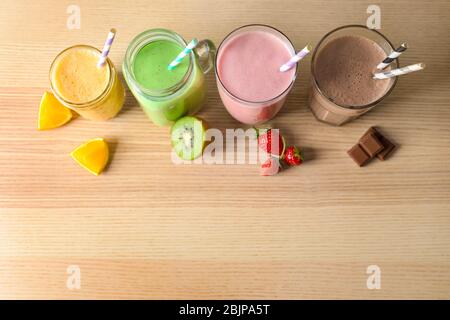 Différents milkshakes en verre sur fond en bois Banque D'Images