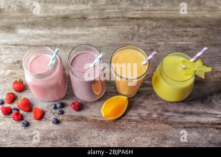 Différents milkshakes en verre sur fond en bois Banque D'Images