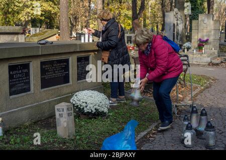 Deux femmes s'occupent d'une tombe avec fleurs et bougies dans le cimetière de Rakowicki à Cracovie, en Pologne, en 2019. Banque D'Images