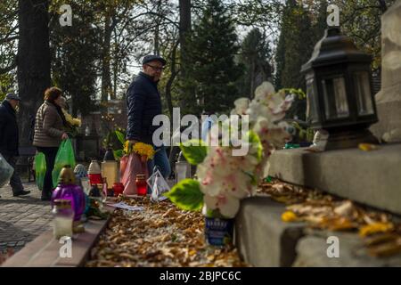 Les gens se promenent dans le cimetière de Rakowicki à Cracovie avec des sacs en plastique remplis de fleurs, Pologne 2019. Banque D'Images