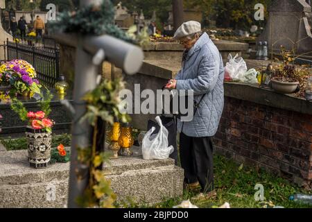 Une femme allume une bougie au cimetière de Rakowicki à Cracovie, Pologne 2019. Banque D'Images