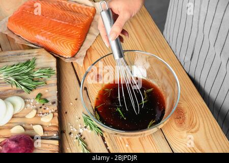 Femme préparant la marinade de soja pour le saumon sur table en bois Banque D'Images