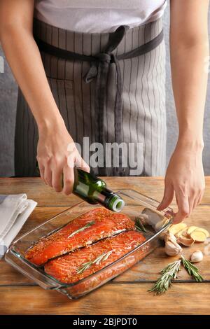 Femme préparant un filet de saumon avec marinade dans un plat de cuisson Banque D'Images