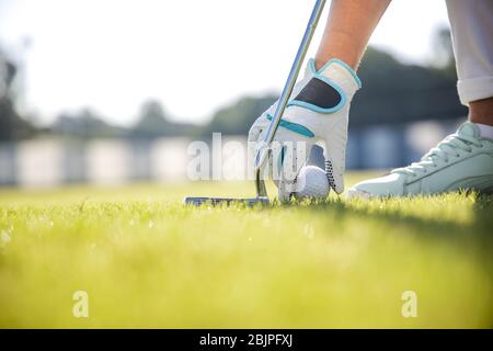 Main dans la main mise sur une balle de golf tee Banque D'Images