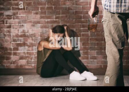 Homme avec bouteille d'alcool et jeune femme contre mur de brique Banque D'Images