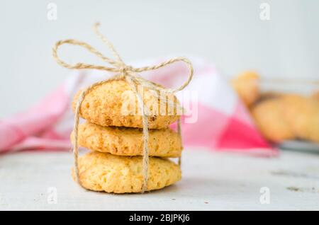 Cookies maison à la noix de coco sur table en bois blanc. Biscuits de noix de coco fraîchement cuits sur fond rustique. Cookies présents. Mise au point sélective. Banque D'Images