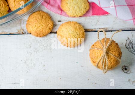 Cookies maison à la noix de coco sur table en bois blanc avec place pour le texte. Biscuits de noix de coco fraîchement cuits sur fond rustique. Cookies présents. Foc sélectif Banque D'Images