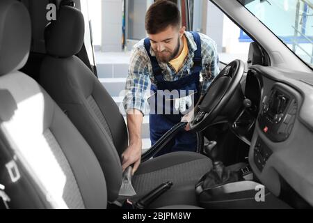 Travailleur masculin utilisant un aspirateur en voiture Banque D'Images