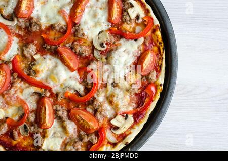 Pizza italienne à la viande chaude sur table blanche. Délicieuse pizza maison avec saucisses salsiccia fresca, fromage Mozzarella, champignons, tomates, poivre. Italien Banque D'Images