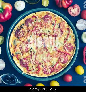 Pizza italienne au vrai pepperoni chaude avec salami et fromage sur la table avec des ingrédients. Délicieuse pizza maison fraîche avec salami, champignons, tomates Banque D'Images