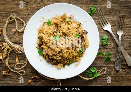 Risotto aux champignons italiens traditionnels maison sur table en bois. Risotto classique aux champignons et légumes servis sur une plaque blanche. Champignons sauvages r Banque D'Images