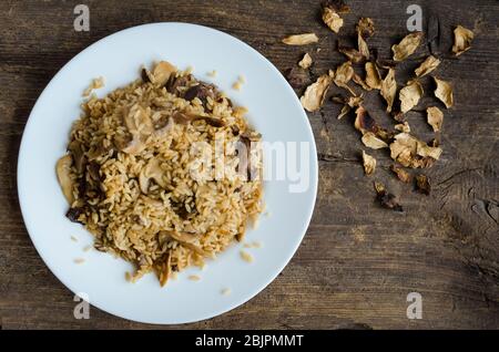 Risotto aux champignons italiens traditionnels maison sur table en bois. Risotto classique aux champignons et légumes servis sur une plaque blanche. Champignons sauvages r Banque D'Images