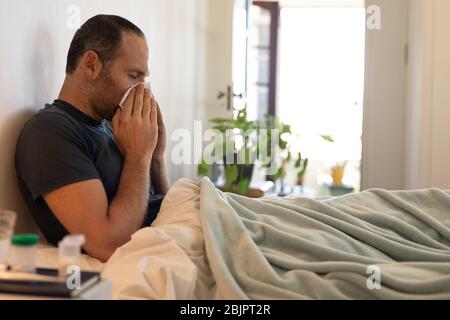 Homme malade caucasien auto-isolation et distanciation sociale dans le verrouillage de quarantaine pendant le coronavirus co Banque D'Images