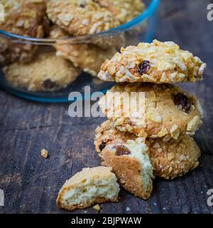 Biscuits faits maison à base de cornflakes et raisins secs sur une vieille table en bois. Biscuits de céréales fraîchement cuits au four à flocons de maïs sur fond rustique. Mise au point sélective. Banque D'Images