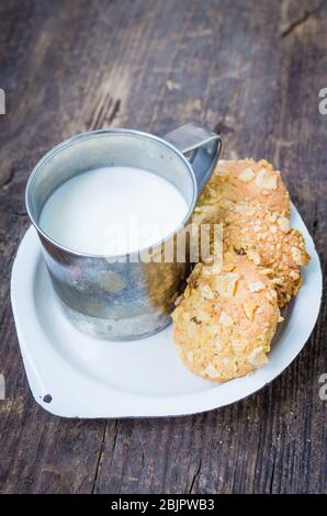 Biscuits faits maison à base de cornflakes et raisins secs avec tasse de lait sur une vieille table en bois. Biscuits de céréales fraîchement cuits au four à flocons de maïs sur fond rustique. Sélectif Banque D'Images