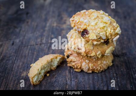 Pile de cornflakes faits maison et biscuits aux raisins secs sur une table en bois ancienne avec place pour le texte. Biscuits de céréales fraîchement cuits au four à flocons de maïs sur fond rustique. Banque D'Images