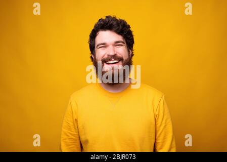 Portrait simple d'un homme souriant barbu dans une humeur positive sur fond jaune. Banque D'Images