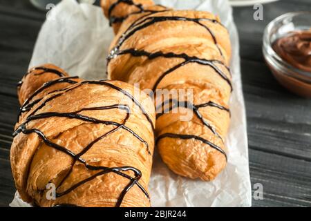 Délicieux croissants avec sirop de chocolat sur table Banque D'Images