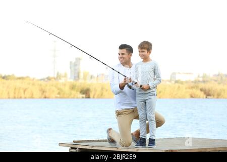 Père et son fils pêchant depuis la jetée sur la rivière Banque D'Images