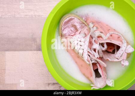 Paire de sneakers roses dans un lavabo en plastique avec suds sur le sol Banque D'Images