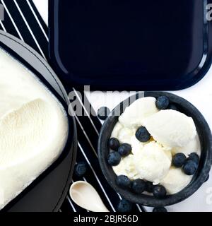 Vue de dessus des pelles de glace à la vanille dans un bol bleu en argile garnie de bleuets frais, copier l'espace sur un fond bleu foncé ffor texte sur la couche Banque D'Images