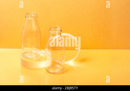 Bouteilles de verre l'emballage du lait sur une sphère claire se tient sur fond orange. Créativité minimaliste toujours la vie Banque D'Images