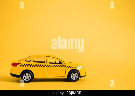 Concept de taxi urbain et de service de livraison. Modèle de voiture de taxi jaune jouet. Espace de copie pour le texte, la bannière. Service de taxi pour la commande d'applications mobiles en ligne. Banque D'Images