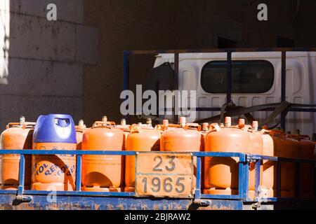 Gérone, Espagne - 24 février 2020: Bouteilles d'orange avec gaz comprimé pour les clients dans un camion à benne ouverte. Livraison urbaine de bouteilles de gaz. frv de la ville réelle Banque D'Images