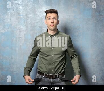 Triste homme montrant ses poches vides sur fond grunge Banque D'Images