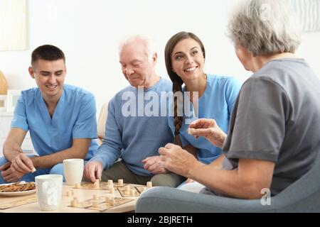 Les personnes âgées jouant au bingo avec leurs soignants à l'intérieur Banque D'Images