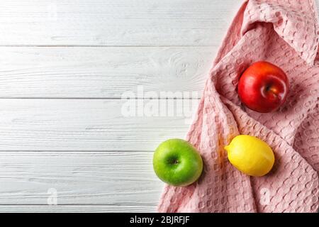 Nettoyez la serviette de cuisine et les fruits sur une table en bois blanc, vue sur le dessus Banque D'Images