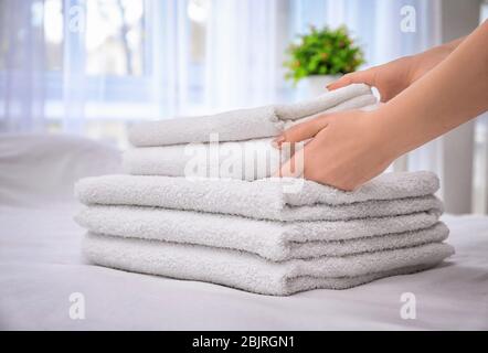 Femme mettant des serviettes de bain blanches sur le lit à l'intérieur Banque D'Images
