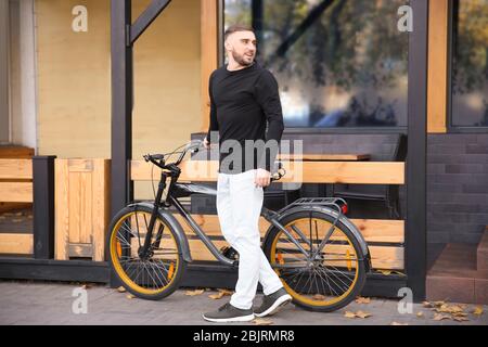 Beau jeune homme hipster avec vélo à l'extérieur Banque D'Images