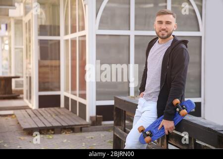 Beau jeune homme hipster avec planche à roulettes en plein air Banque D'Images