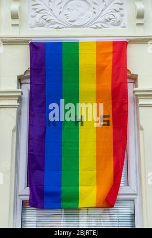 Un drapeau arc-en-ciel avec la lettre NHS sur elle volant sur la fenêtre avant d'une maison en appui pendant Covid-19 Banque D'Images