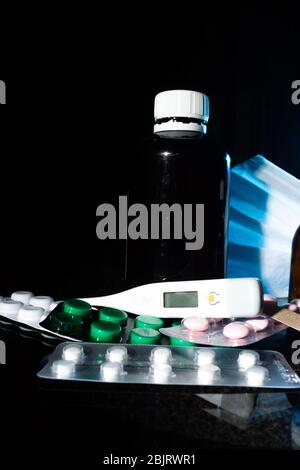 pots médicaux, thermomètre, seringue, masque de gaze et médicaments pilules, médicaments sur fond noir de verre gros plan. espace de copie Banque D'Images