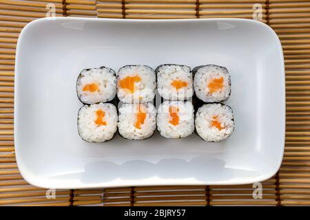 Syake Maki classique avec saumon frais et wasabi. Petits pains Hosomaki, petits pains simples, petits pains, concombre. Vue de dessus sur une plaque blanche. Banque D'Images