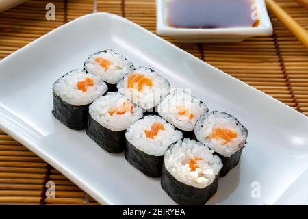 Syake Maki classique avec saumon frais et wasabi. Petits pains Hosomaki, petits pains simples, petits pains, concombre. Sur une plaque blanche. Banque D'Images