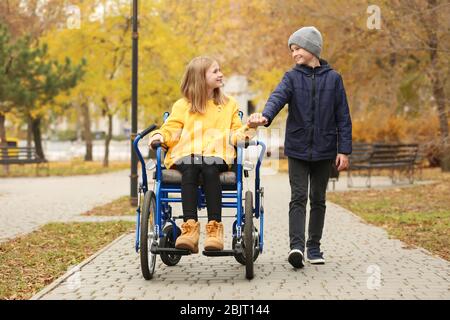 Petite fille en fauteuil roulant avec frère à l'extérieur Banque D'Images