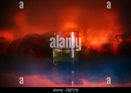 Cocktail dans un verre de rox de verre avec fumée de glace brûle sur un fond de Lava luxuriant. Gros plan Banque D'Images